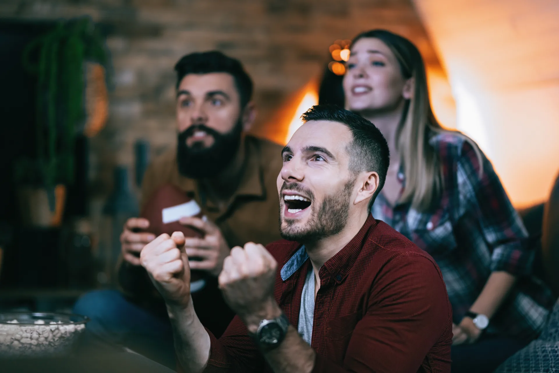 Young man cheering for his team while watching sports championsh
