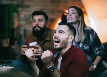 Domine a estratégia: blackjack online para além da sorte Young man cheering for his team while watching sports championsh